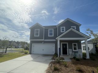 A modern gray home with a charming porch and landscaped yard in Cypress Preserve: Arbor Collection by Lennar (Moncks Corner, SC).