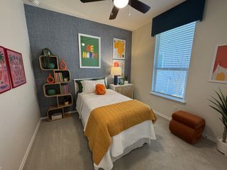 Model Home A cozy bedroom with vibrant artwork, a yellow quilt, and stylish shelving with green accents.