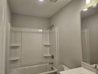 A modern bathroom with a sleek white tub, built-in shelves, and sophisticated lighting.