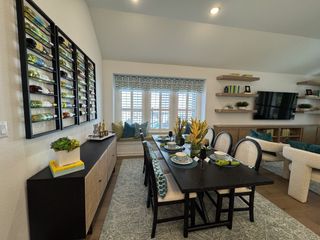 Model Home A spacious kitchen featuring a white and wood island, pendant lighting, and decorative glass cabinets