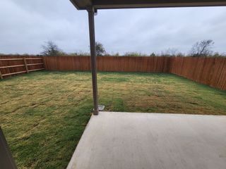 Model Home A spacious backyard with a neatly sodded lawn and wooden fencing.