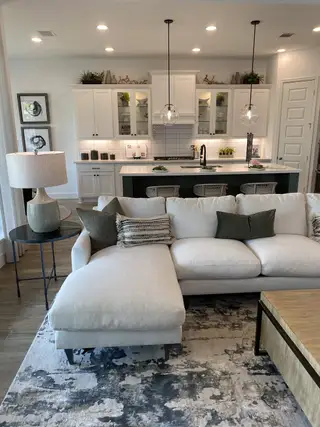 An open-concept living and kitchen area with a spacious sectional, pendant lights, and wood-look flooring.