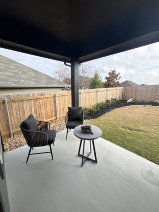 A charming covered patio with cozy outdoor seating and a private backyard in Vista Ridge by HistoryMaker Homes (Live Oak, TX).