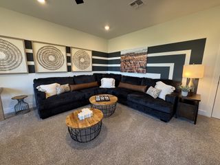 Model Home A cozy living room featuring a plush sectional sofa, geometric wall art, stylish tables, and warm lighting.