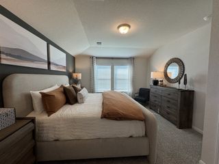 Model Home A cozy bedroom featuring elegant decor, a plush bed, and ample natural light through large windows.