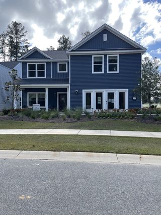 Street view A modern blue two-story home with white trim and manicured landscaping in Watson Hill by Ashton Woods (Summerville, SC).