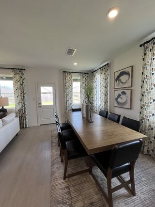 A modern dining area with a wooden table, black chairs, abstract art, and patterned curtains for an inviting atmosphere.