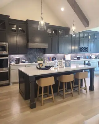 A modern kitchen with dark cabinets, a spacious island, and elegant pendant lighting.