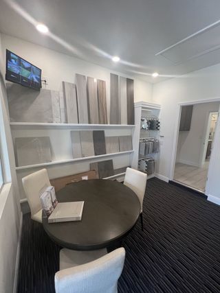 A modern design studio with a round table, sample boards on display, and contemporary lighting.