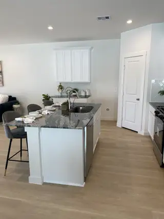 A modern kitchen with granite countertop island, sleek cabinets, and cozy seating, offering a stylish and functional space.