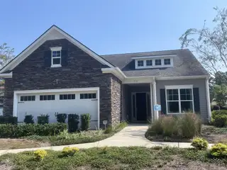 Street view A charming stone-accented home with manicured landscaping in Four Seasons at Lakes of Cane Bay by K. Hovnanian® Homes (Summerville, SC).
