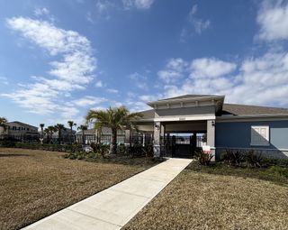 A well-appointed clubhouse entrance with tropical landscaping and a welcoming design in Oak Pointe by D.R. Horton (Apopka, FL).