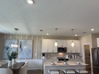 A modern kitchen with sleek white cabinetry, pendant lighting, and a spacious island, seamlessly connected to a cozy dining area.