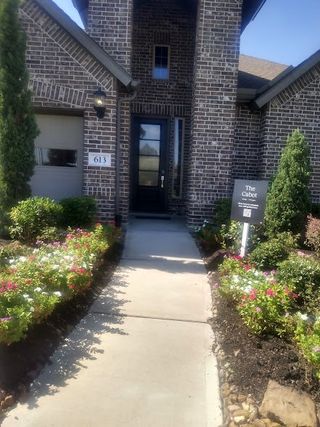 Street view A grand entrance with elegant brickwork and vibrant landscaping welcomes you to this stunning home in Westwood by Lennar (League City, TX).