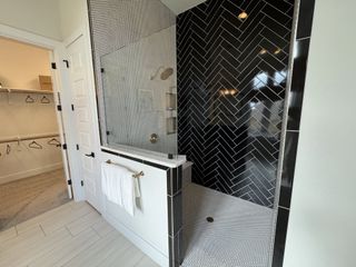 A stylish walk-in shower with a bold black herringbone tile design, sleek glass doors, and modern gold fixtures for a chic feel.