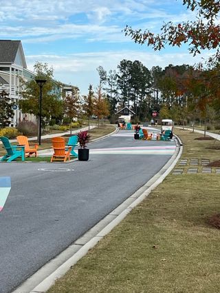 A vibrant street scene with colorful chairs and lush trees in Nexton - Midtown - The Village Collection by David Weekley Homes (Summerville, SC).