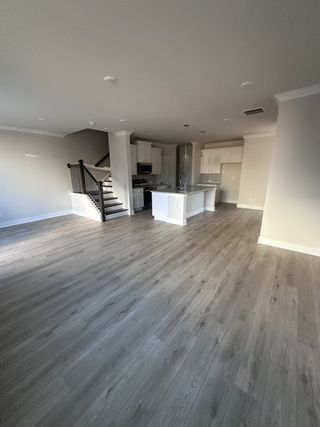 A modern open-concept living space with sleek hardwood floors, a stylish kitchen island, and elegant stairway.