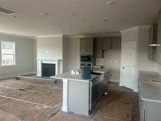 Modern kitchen with an island, built-in fireplace, gray cabinets, and large windows for natural light.