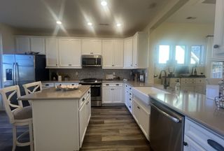 A modern kitchen features sleek quartz countertops, stainless steel appliances, and elegant white cabinetry for a stylish look.