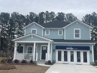 A charming blue home with a welcoming porch in The Coves at Lakes of Cane Bay by Meritage Homes (Summerville, SC).