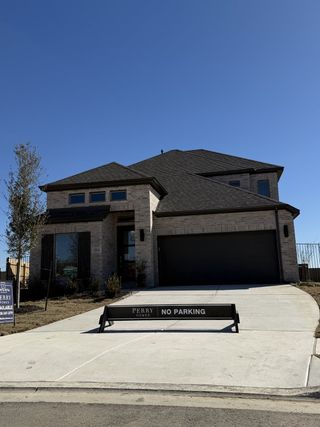 A modern brick home with a spacious driveway in Santa Rita Ranch by Perry Homes, located in Liberty Hill, TX.