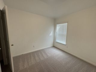 A cozy, carpeted room with neutral walls and natural light filtering through window blinds.
