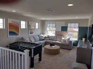 A cozy family room with a large sectional sofa, colorful wall art, and a foosball table for entertainment.