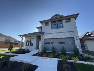 Street view A modern two-story home with sleek finishes and landscaped front yard in Deerbrooke Cottages by Chesmar Homes (Leander, TX).