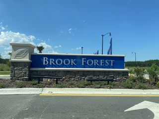 Brook Forest entrance with stone pillars and lush landscaping at Holly Landing at SilverLeaf by Dream Finders Homes (St. Augustine, FL).