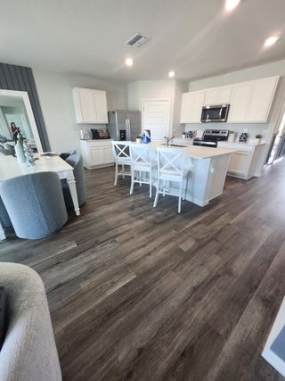 Model Home A modern kitchen with white cabinets, stainless appliances, and a cozy breakfast bar featuring elegant seating.
