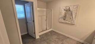 A spacious bathroom with a modern glass shower, neutral tones, and elegant artwork on the wall.