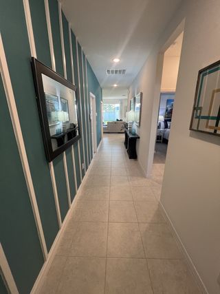 A modern hallway with elegant teal paneling, large mirrors, and a bright, open-concept layout.