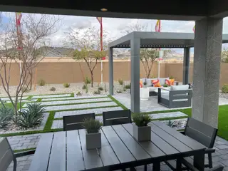 A stylish patio features modern seating, greenery, and a pergola, perfect for outdoor relaxation and entertainment.