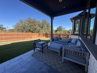 Model Home A cozy patio with stylish outdoor seating and lush backyard views.