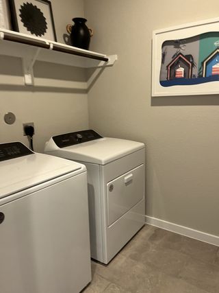 A functional laundry room with modern washer, dryer, shelving, and stylish wall art.