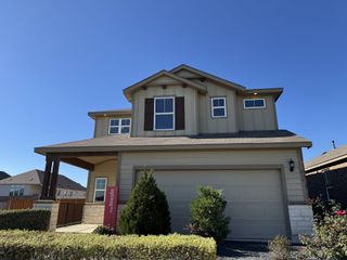 Street view A charming beige home with landscaped front in Sunfield by Centex, Buda, TX.