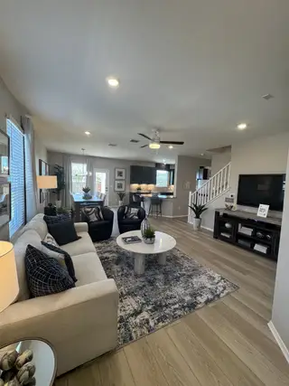 A modern living room with cozy seating, sleek decor, and warm lighting, featuring a stylish area rug and wooden flooring.