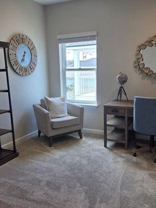 A cozy study with a plush armchair, rustic clock, and desk, offering a serene space for work or reading.