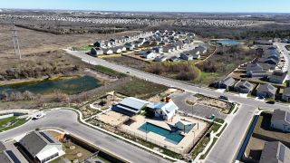 Community Amenities Aerial view of Greenwood by Lennar in Pflugerville, TX, featuring homes, a pond, and community amenities.