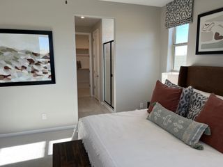 A cozy bedroom featuring elegant bedding, abstract wall art, and a walk-in closet with ample natural light.
