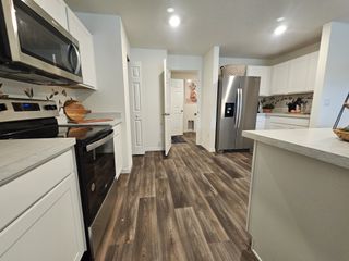 A modern kitchen featuring stainless steel appliances, sleek white cabinets, and stylish wood flooring.