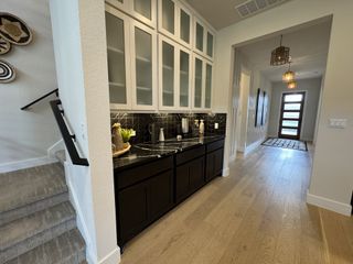 A modern butler’s pantry with black cabinetry, a sleek black backsplash, and frosted upper cabinets, adding functional elegance to the home’s layout.