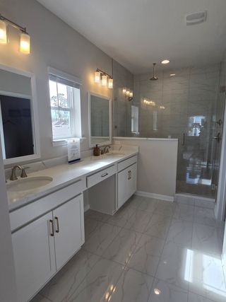 A sleek bathroom with dual sinks, ample lighting, a spacious shower, and elegant tile flooring.