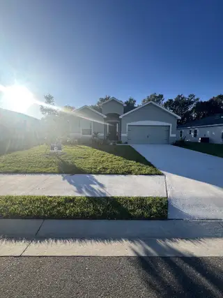 A charming gray home with a lush lawn in Otter Woods Estates by Highland Homes of Florida (Auburndale, FL).