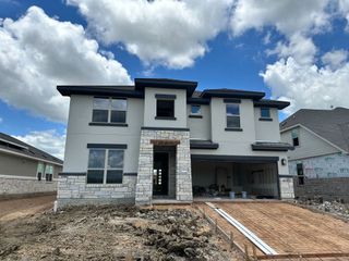 Street view A modern two-story home with stone accents and a landscaped yard in Carillon by Brightland Homes (Manor, TX).