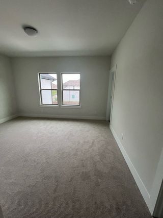 A bright room with soft carpet, large windows, and neutral walls, perfect for a cozy bedroom or an inspiring home office.