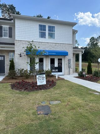 A charming home with a blue awning and landscaped yard in Avery Landing by DRB Homes (Mcdonough, GA).
