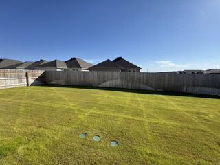 Model Home This spacious backyard at Eastern Wells by Stylecraft Builders (Jarrell, TX) offers ample room for outdoor living and entertainment under a bright, sunny sky.