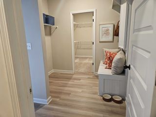 A mudroom with built-in seating and storage, leading to a walk-in closet in Kingston by DRB Homes (Locust Grove, GA).