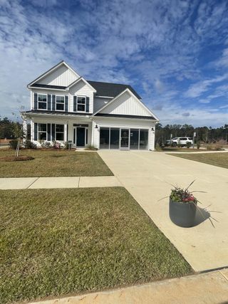 A charming white home with black shutters and a spacious driveway in Parker's Preserve by Eastwood Homes (Ridgeville, SC).